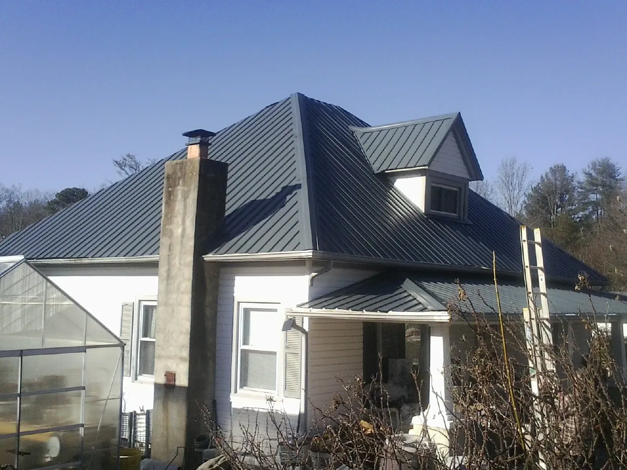Dark blue standing seam metal roof on a white farmhouse with dormer — Slate & Tile Roof Repair by Roofing Brothers in East Haddam