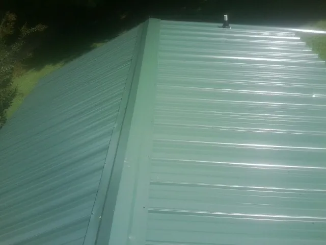 New green metal panels meeting at the ridge of a roof — Flat Roof Repair work by our crew in East Haddam