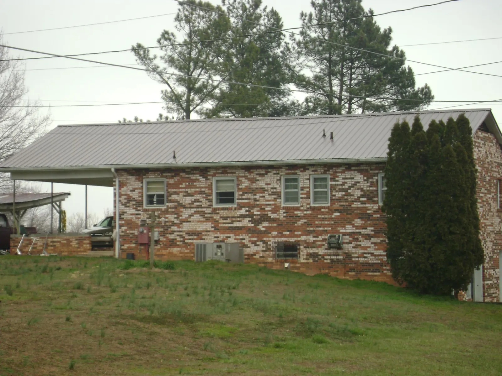 Gray metal roof on a brick split level home with a carport in East Haddam