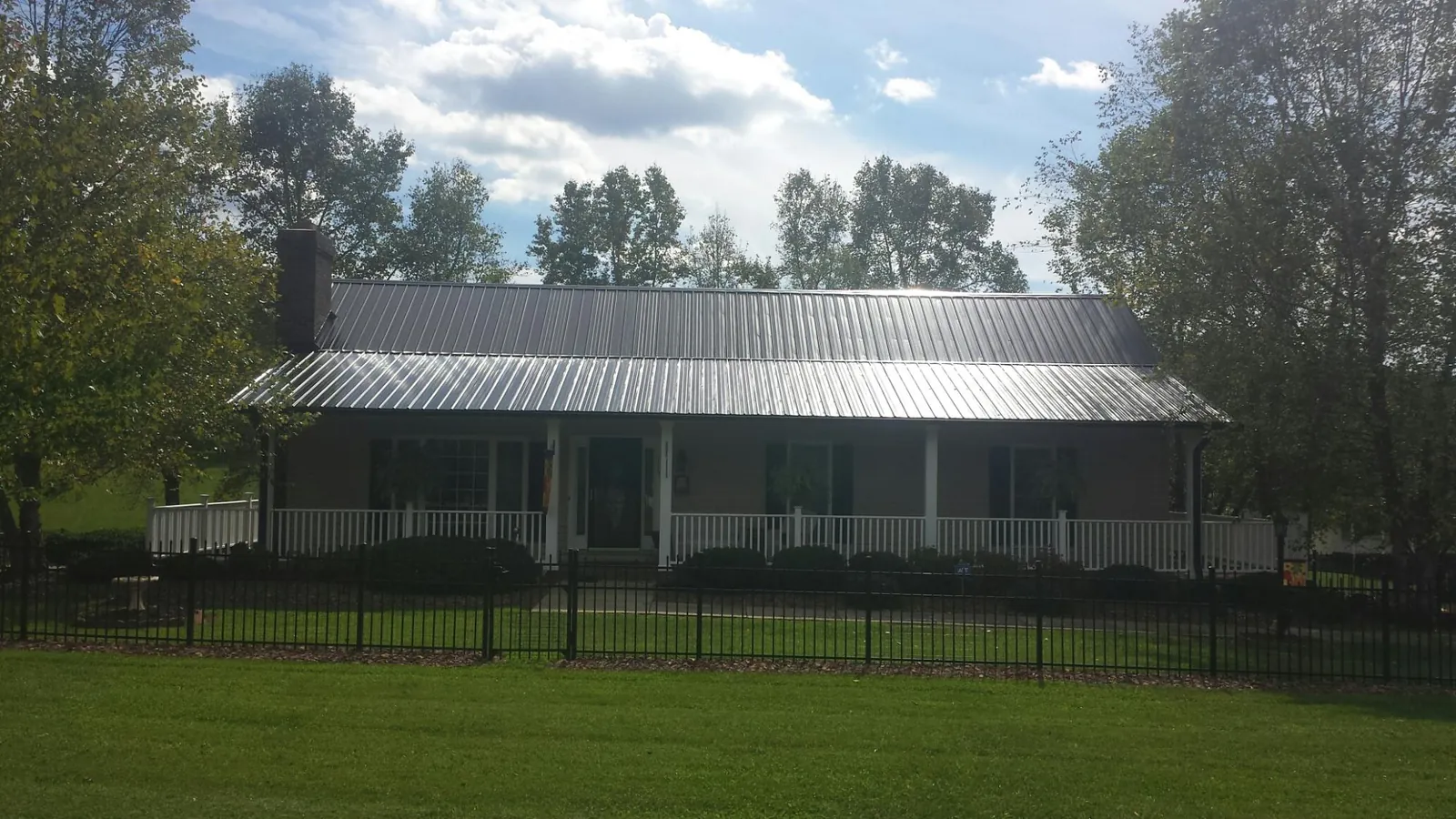 Gray metal roof on a brick ranch with a full width front porch — Gutter Guard Installation work by our crew in East Haddam