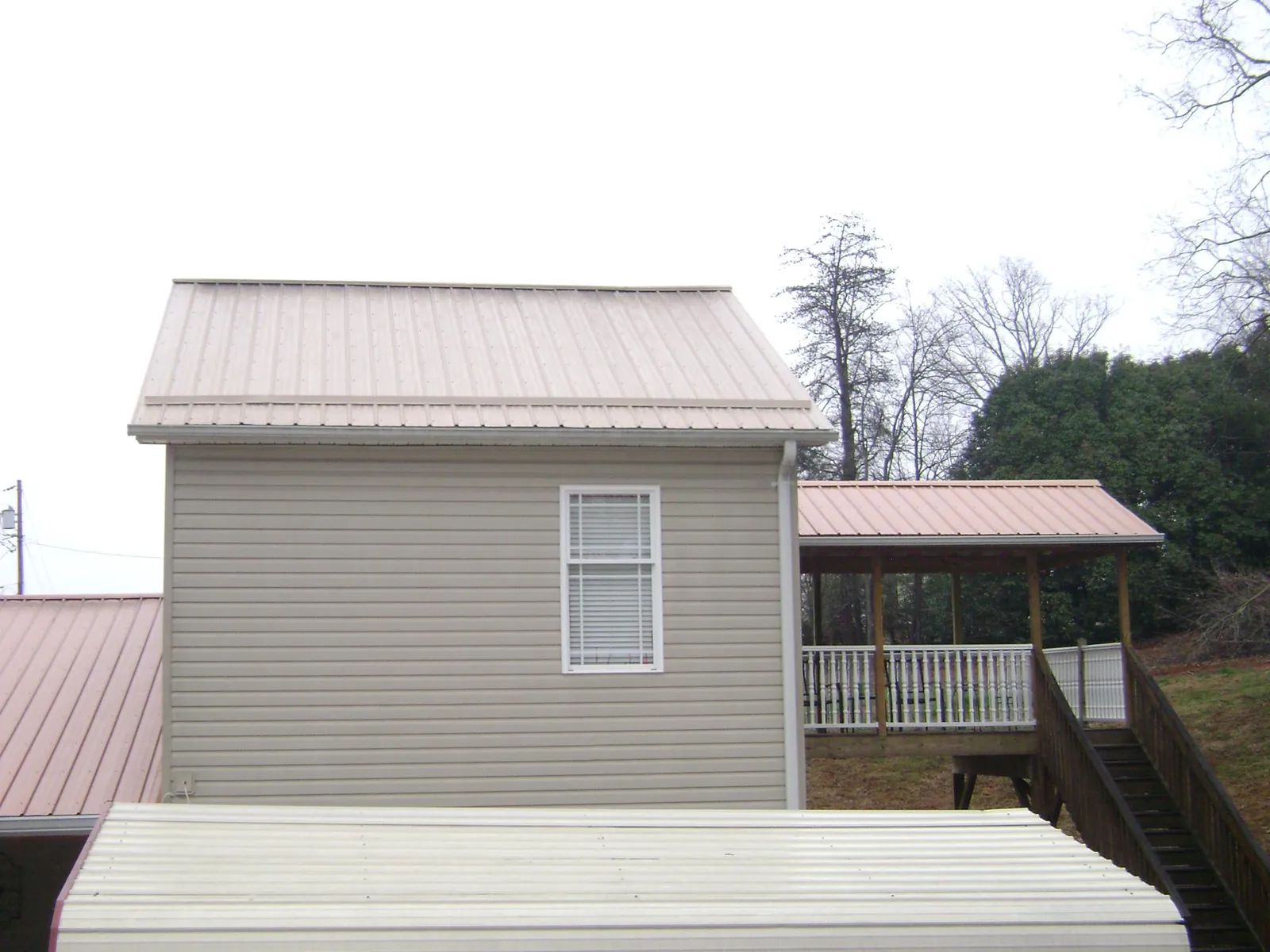 Tan metal roofs on a two story addition and attached porch, from a Roof Replacement job in East Haddam