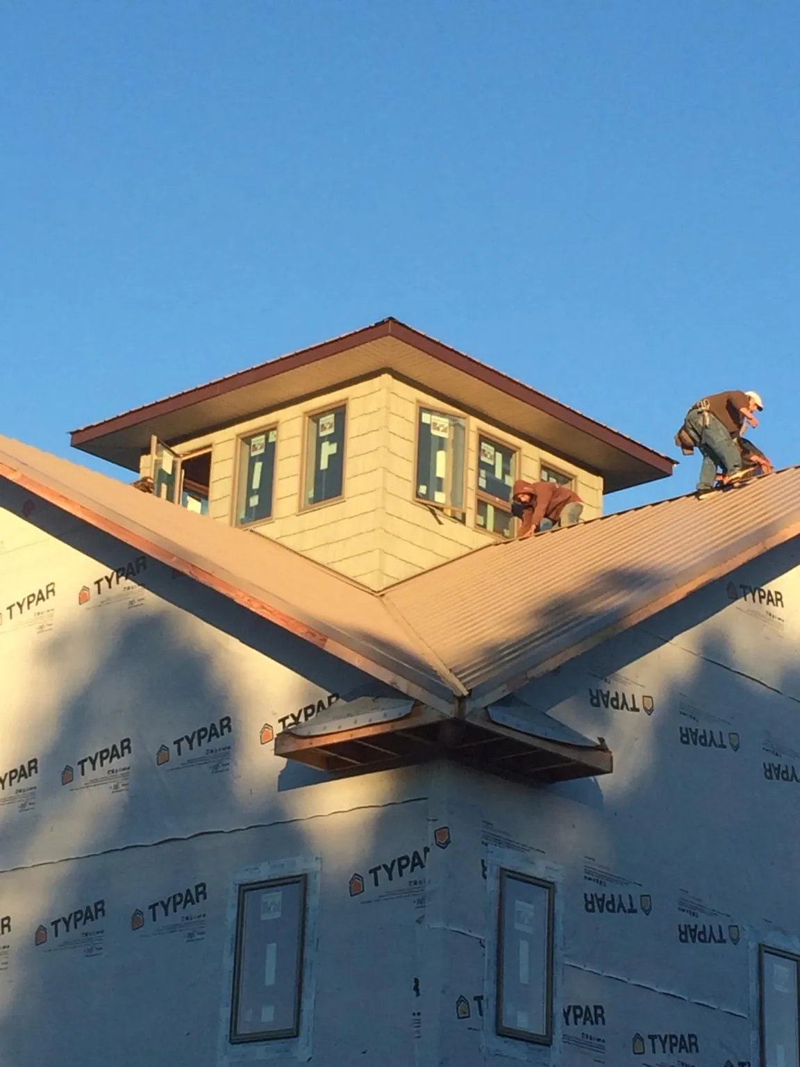 Roofers working around a rooftop cupola on a new metal roof at sunset — Roof Waterproofing in East Haddam by Roofing Brothers